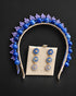 A blue beaded and crystal tiara headband displayed with a matching pair of flower-shaped drop earrings on a beige jewelry card. The headband features blue beads, blue crystal leaves, and a gold-toned band, while the earrings have blue crystals and gold-toned metal.
