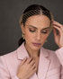 A woman wearing a light pink blazer and gold birdcage veil for spring racing 2026