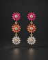 A pair of gold dangle earrings featuring three flower-shaped drops: vibrant pink, orange, and clear crystal petals, displayed against a dark background.