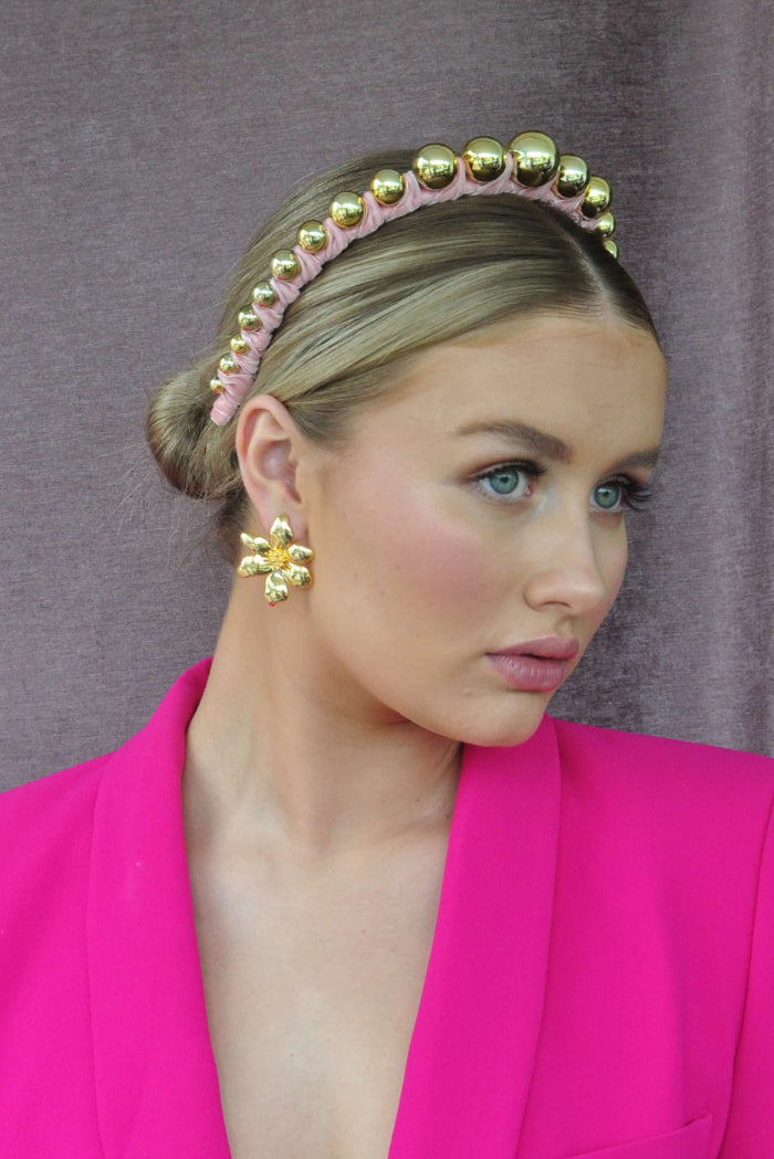 Woman wearing a pink velvet headband with gold beads
