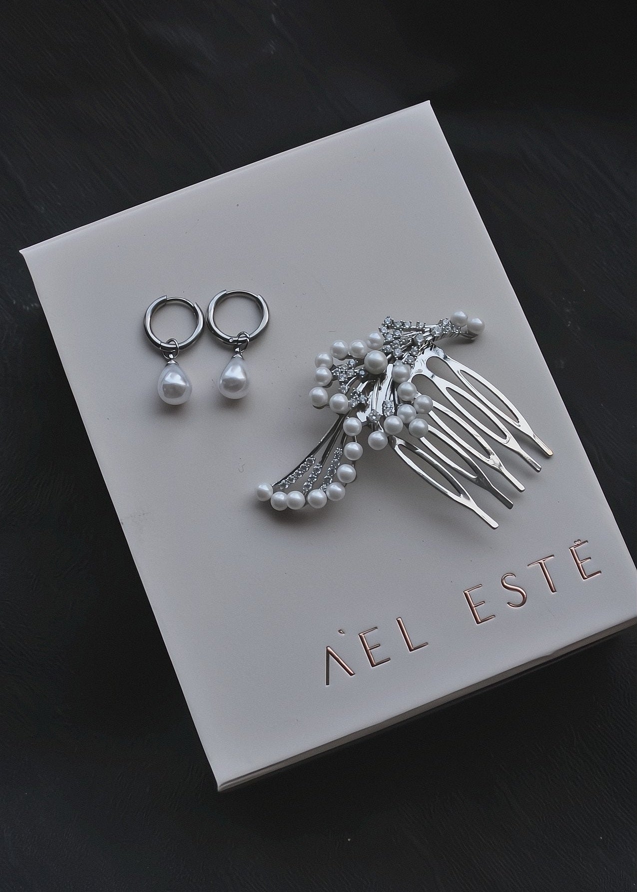 Jewelry set including earrings and a comb on a 'Aèl Esté' branded card.