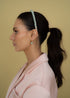 Woman with a ponytail wearing a mint beaded headband against a beige background with matching mint earrings